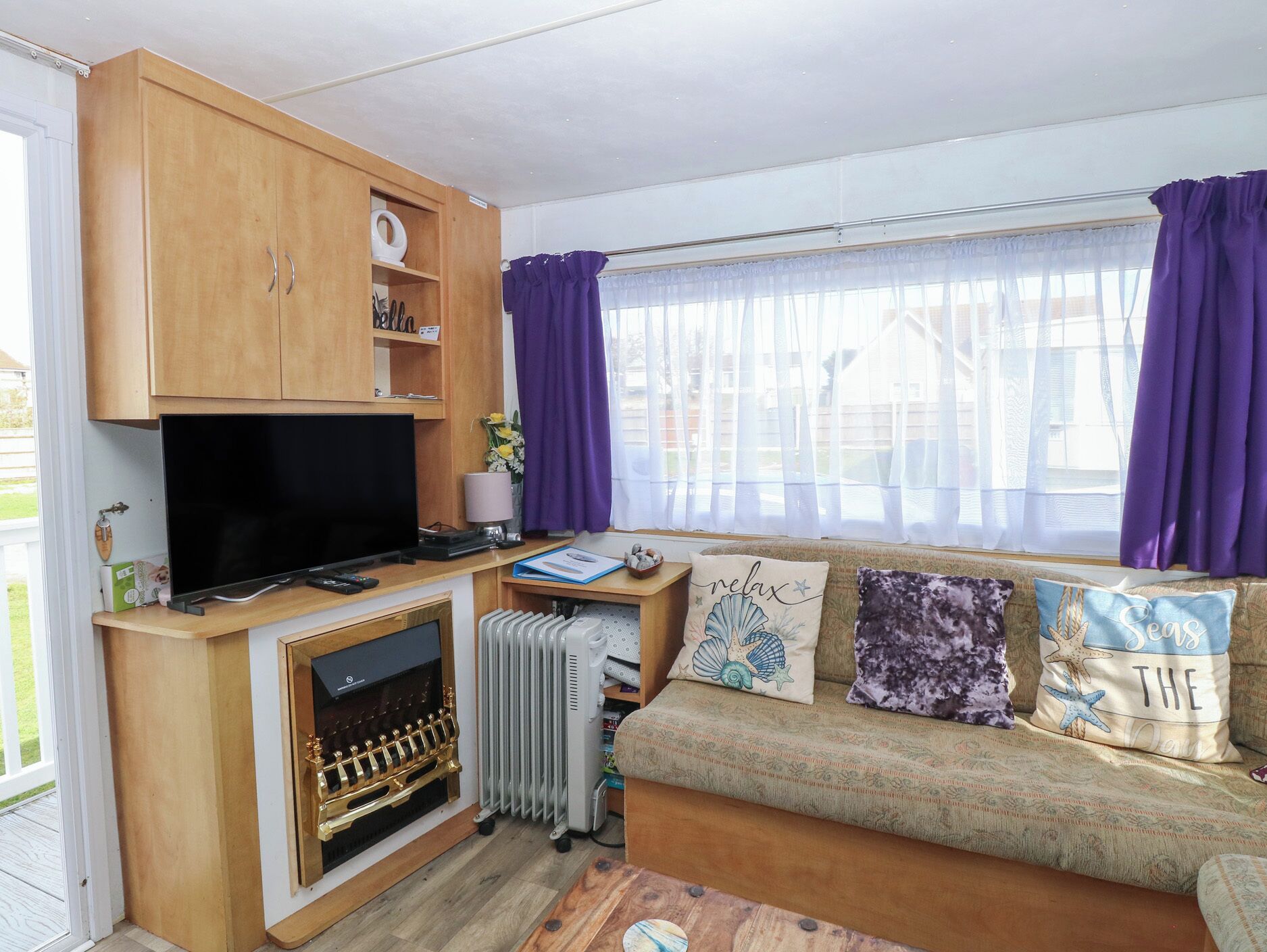 A compact living space with a TV, sofa, and wooden cabinets.