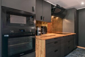 Una cocina moderna con microondas, horno y cafetera integrados.