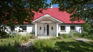 A white building with a red roof, a central entrance, and a stone pathway leading to it. - Comfortable house with a swimming pool and sauna (Anielino)