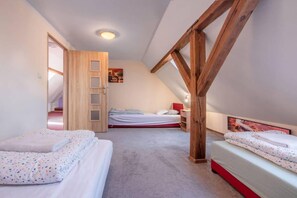 Ein Schlafzimmer mit zwei Betten, einer Holztür und einer schrägen Decke.