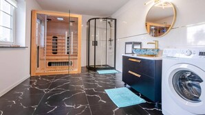 A modern bathroom with a glass-enclosed shower, a wooden vanity, a washing machine, and a large mirror. - Comfortable house with a swimming pool and sauna (Anielino)