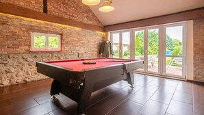 Een biljart tafel in een ruimte met een bakstenen muur, een raam en uitzicht op de omgeving.