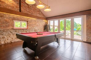 A pool table in a room with a brick wall, a window, and a view of the outdoors. - Atmospheric holiday home with a swimming pool (Anielino)
