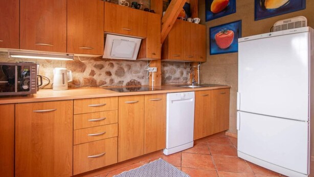 Een keuken met houten kastjes, een magnetron, een vaatwasser en een koelkast.
