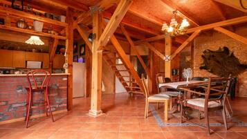 A rustic wooden interior with a kitchen, dining area, and a staircase.