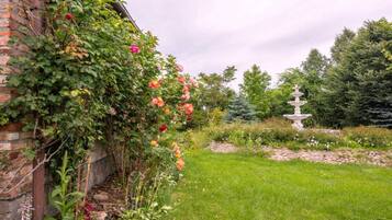 A garden with a brick wall, flowering plants, and a stone fountain.