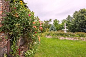 A garden with a brick wall, flowering plants, and a stone fountain. - Atmospheric holiday home with a swimming pool (Anielino)