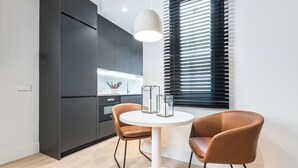 Una cocina moderna con armarios oscuros, una mesa de comedor blanca y dos sillas marrones.