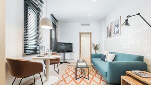 Una sala de estar moderna con un sofá color turquesa, una mesa de centro, un televisor y un comedor con una silla y una mesa.