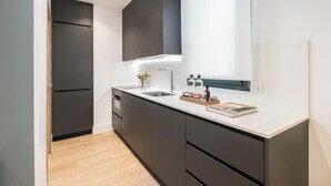 Una cocina moderna con armarios oscuros, una encimera blanca y un horno empotrado.