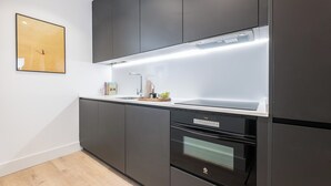 A modern kitchen with dark cabinetry, a stainless steel range hood, and a built-in oven. - Doctor Castelo xxviii (Madrid)