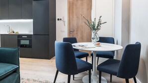 A modern kitchen with dark cabinets, a wooden door, and a dining area with a white table and blue chairs. - Doctor Castelo xxviii (Madrid)