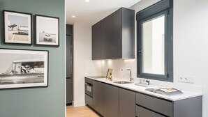 A modern kitchen with dark cabinetry, a white countertop, and a large window. - Doctor Castelo XL - One Bedroom Apartment, Sleeps 2 (Madrid)