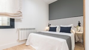 A modern bedroom with a bed, bedside tables, a radiator, and a window with curtains. - Doctor Castelo XL - One Bedroom Apartment, Sleeps 2 (Madrid)