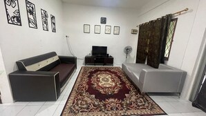 Un salon avec un canapé, un téléviseur, un tapis décoratif et des œuvres d’art murales.