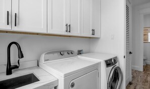 A laundry area with a washing machine, a dryer, and a sink. - New! Beautiful beach house with heated Pool & Spa! (Holmes Beach)