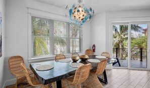 Un coin repas avec une table ronde, des chaises en osier et un luminaire suspendu au plafond.