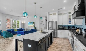 Una cocina moderna con una isla central, muebles blancos y electrodomésticos de acero inoxidable.