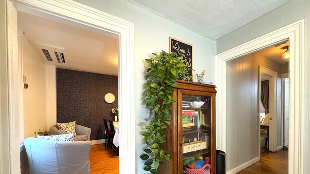 Un pasillo con piso de madera, un sofá blanco, pared oscura con diseño y una estantería con un letrero que dice "Welcome to a RIB".