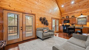 A spacious living room with a grey sofa, a patterned rug, and a wooden ceiling. - Couple's Retreat | Fire Pit | Hot Tub (Broken Bow)