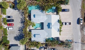 Eine Vogelperspektive eines Gebäudes mit Schwimmbad, Parkplatz und umliegenden Palmen.