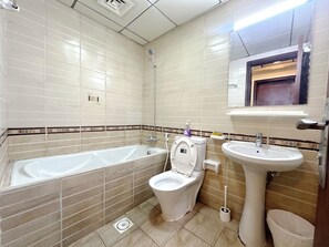 Bañera con ducha, toallas, papel higiénico