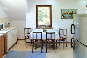 A compact kitchen with a dining table, chairs, a refrigerator, and a window with a view of greenery. - Holiday Apartment With Fireplace, Lake View (Lipnica)