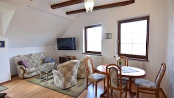 A living room with a sofa, chairs, a TV, and a dining table.