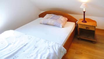 A single bed with a wooden headboard, a bedside table with a lamp, and a nightstand.