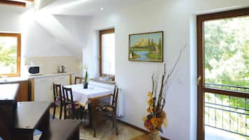 A dining area with a table and chairs, a kitchen with a microwave, and a painting on the wall.