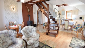 A spacious living area with a wooden staircase, a dining table with chairs, and a kitchen area. - Holiday Apartment With Fireplace, Lake View (Lipnica)