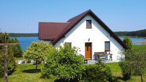 A white house with a brown roof, a wooden door, and a small window. - Holiday Apartment With Fireplace, Lake View (Lipnica)