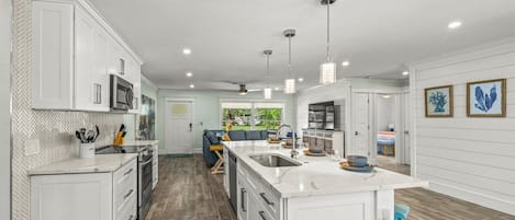 A modern kitchen with white cabinetry, a large island, and pendant lighting.