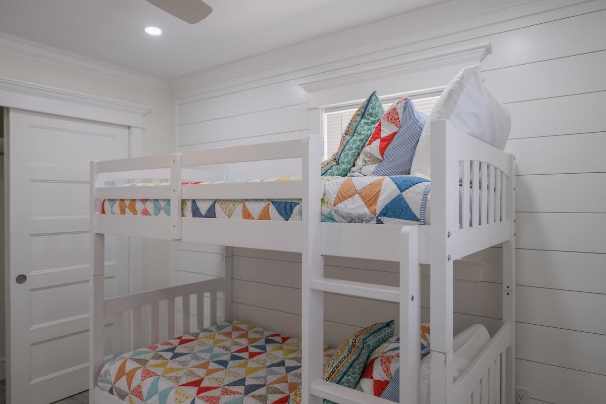 A bunk bed room with white walls and a door.