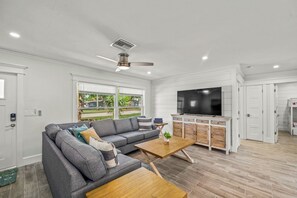 A modern living room with a grey sofa, wooden coffee table, and a TV.