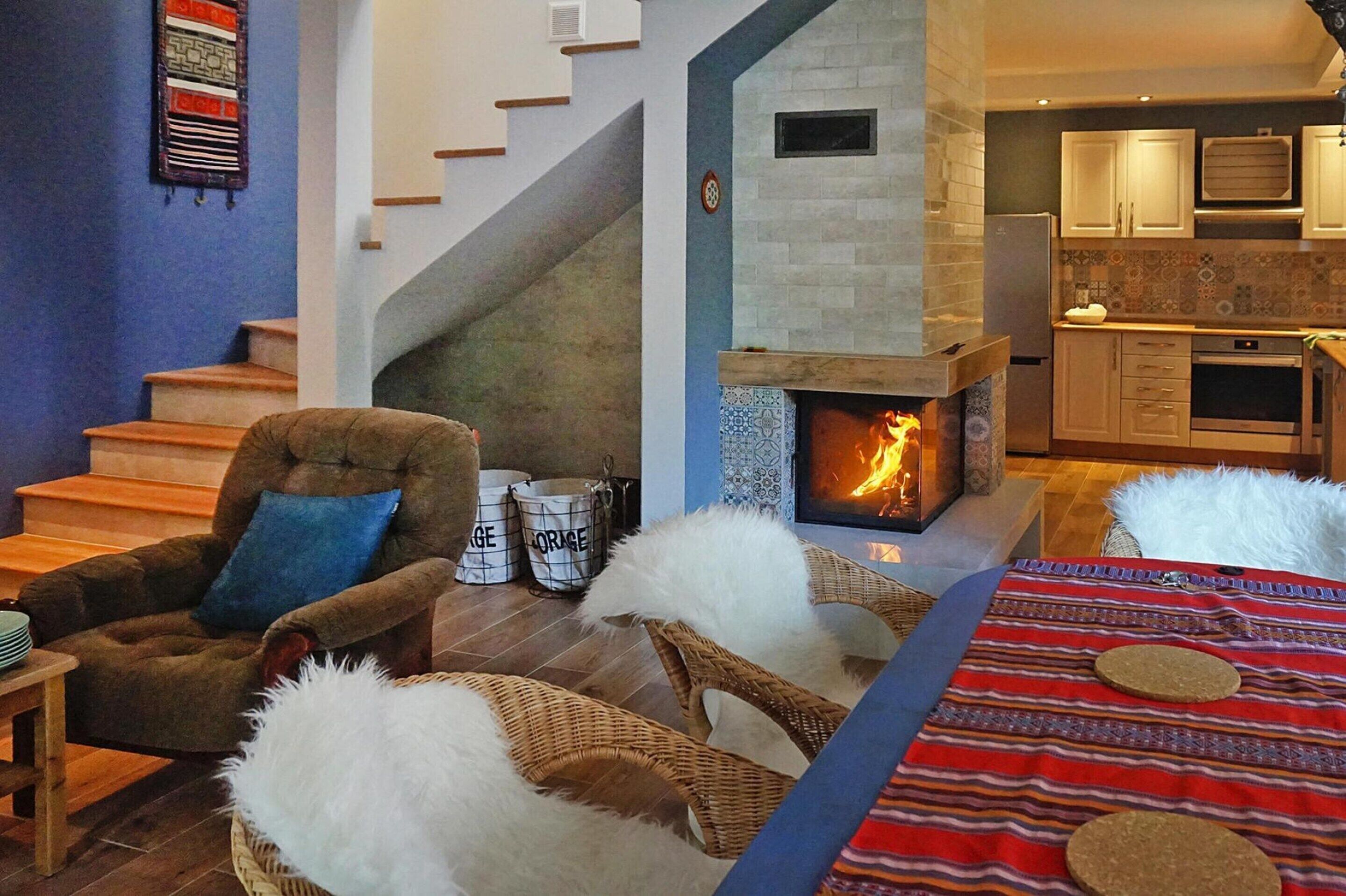 A living room with a fireplace, a staircase, and a kitchen area.