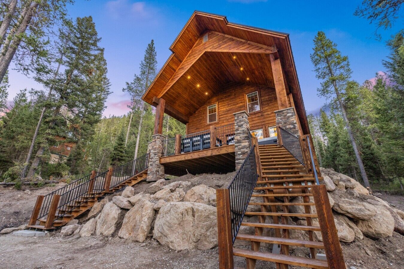 A wooden cabin with a stone foundation, a covered porch, and a staircase leading to the entrance.