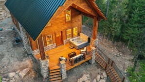 Een houten hut met een jacuzzi, buitenzitplaatsen en een stenen fundering.