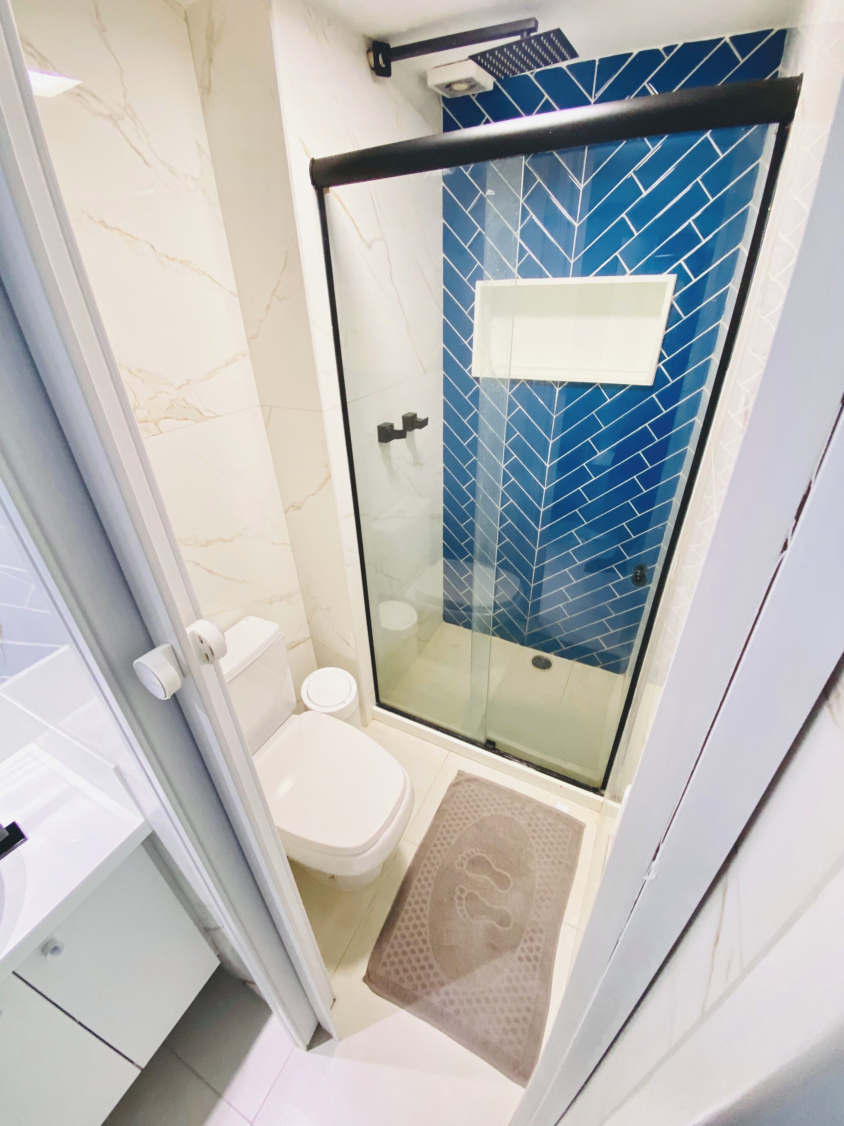 A bathroom with a glass-enclosed shower, a toilet, and a sink.