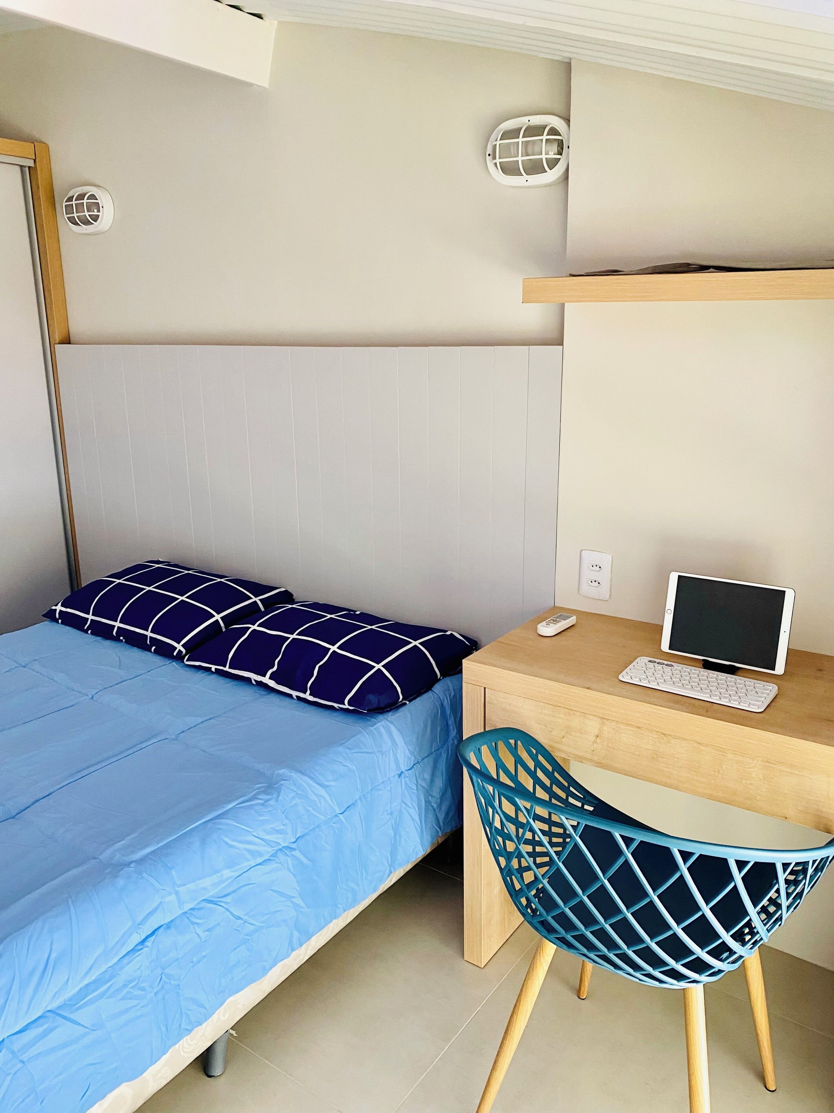 A bedroom with a bed, a desk with a computer, and a chair.
