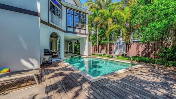 Ein Poolbereich mit Holzterrasse, Grillplatz und überdachter Terrasse.