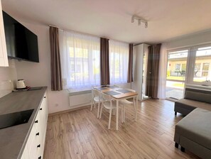 A modern kitchen with a built-in stove, a dining area with a table and chairs, and a sofa. - Holiday Cottages Right on the Beach (Ustronie Morskie)