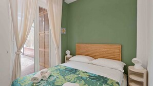 A bedroom with a bed, curtains, a wooden headboard, and a nightstand. - Blue Sign – Your corner of the sea in Le Grazie, PortovenereLocated in the picturesque village of Le Grazie, a hamlet of the municipality of Portovenere, Blue Sign is a holiday home with a refined and welcoming style, perfect for those looking for a re (Le Grazie)