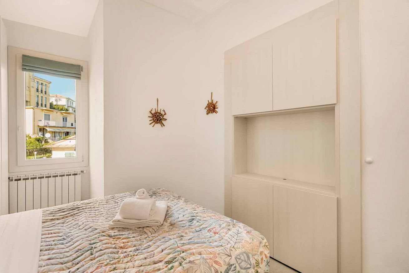 Un dormitorio con cama, ventana y un armario blanco.