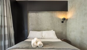 A modern bedroom with a large bed, a headboard, a wall-mounted light, and a bedside table with a book. - Modern Studio Just 500m From Metro Station Edk0714 (São Paulo)