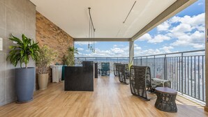 Un balcon avec vue sur la ville, un plancher en bois, des meubles en osier et des plantes en pot.