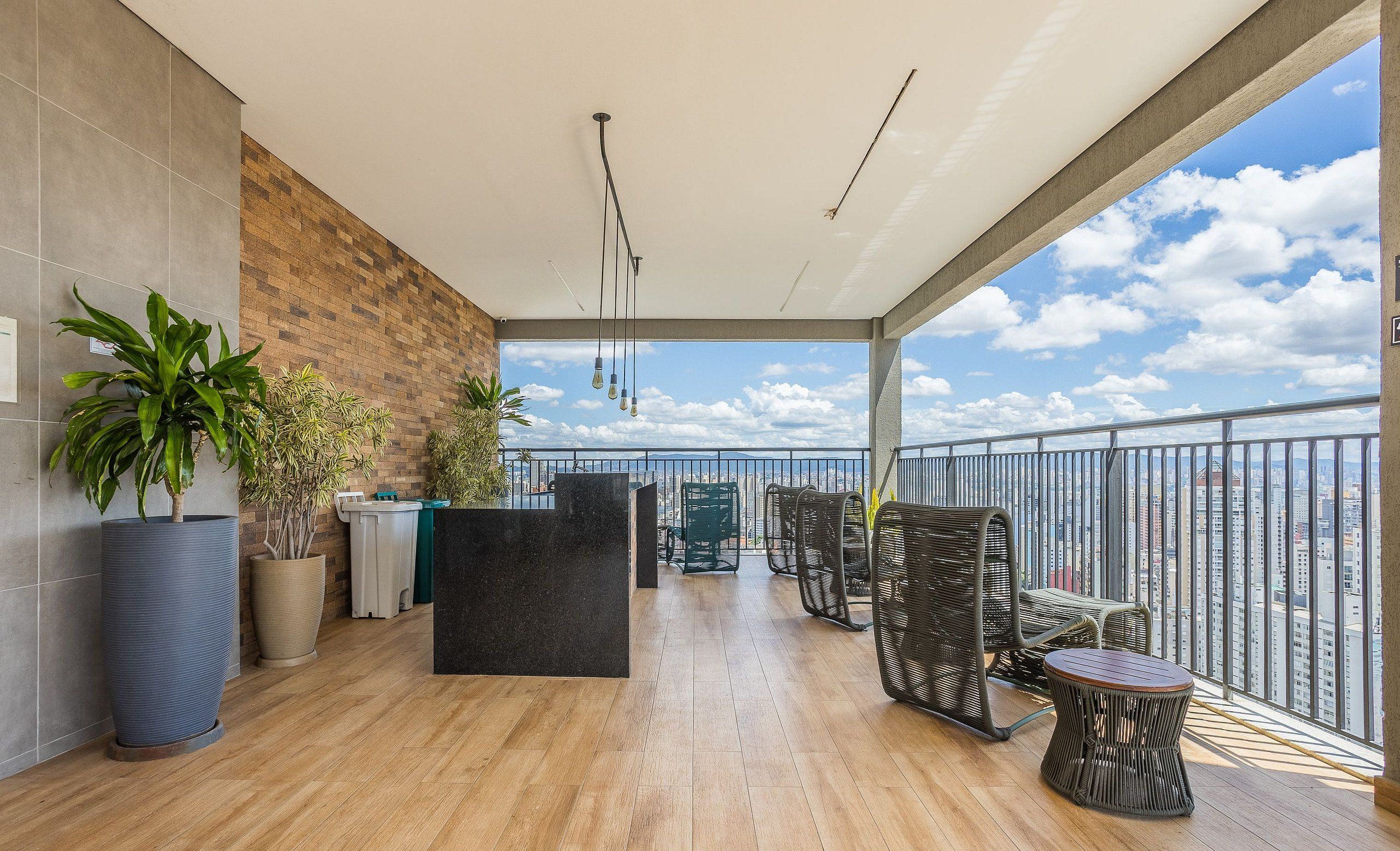 Un balcon avec vue sur la ville, un plancher en bois, des meubles en osier et des plantes en pot.