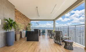 A balcony with a view of the city, wooden flooring, wicker furniture, and potted plants. - Modern Studio Just 500m From Metro Station Edk0714 (São Paulo)
