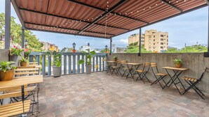 An outdoor patio with tables and chairs, potted plants, and a view of buildings in the background. - Casa Presentación Adaz Hotel (Santa Marta)