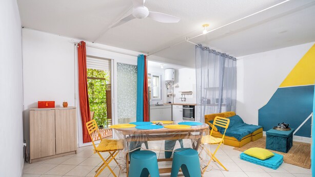 Een moderne woonkamer met een eettafel, stoelen, een bank en een plafondventilator.